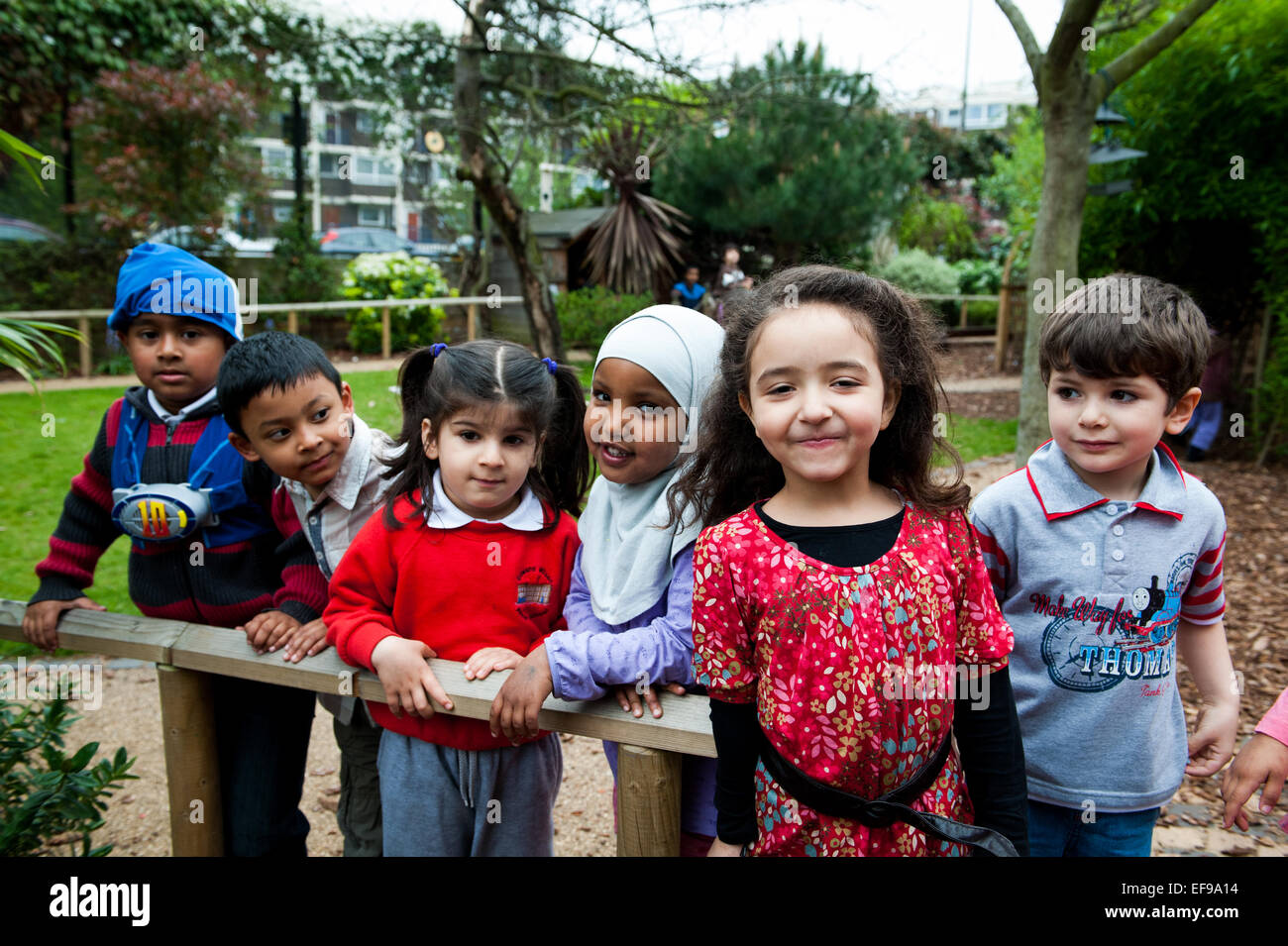 Sorridenti dei bambini che giocano nel parco giochi della scuola primaria in London W2 Foto Stock