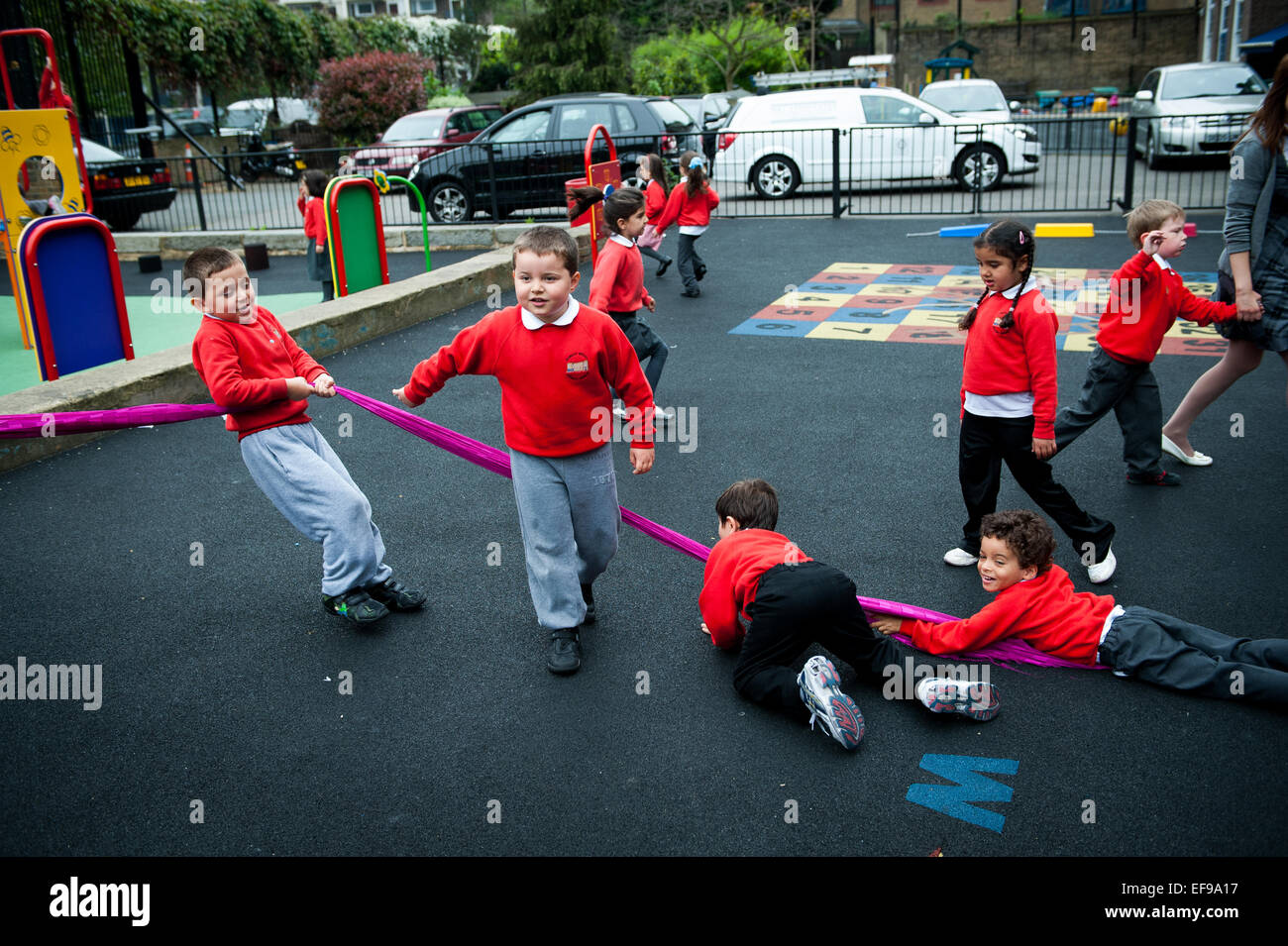 Sorridenti dei bambini che giocano nel parco giochi della scuola primaria in London W2 Foto Stock