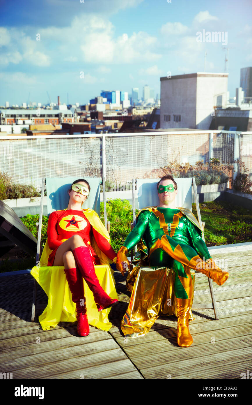 Il supereroe giovane seduto sul tetto della città Foto Stock