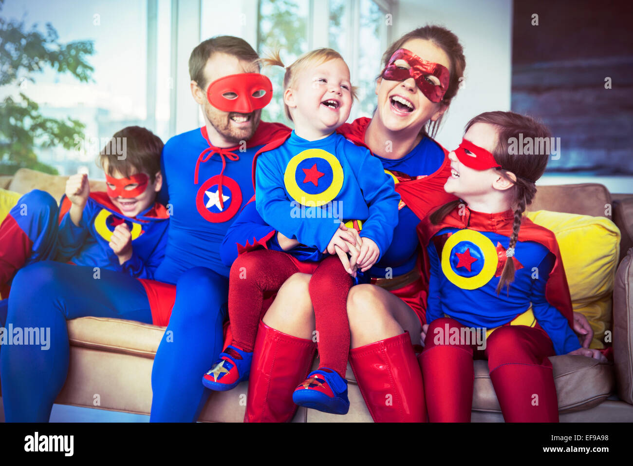 Famiglia di supereroi ridere sul divano Foto Stock