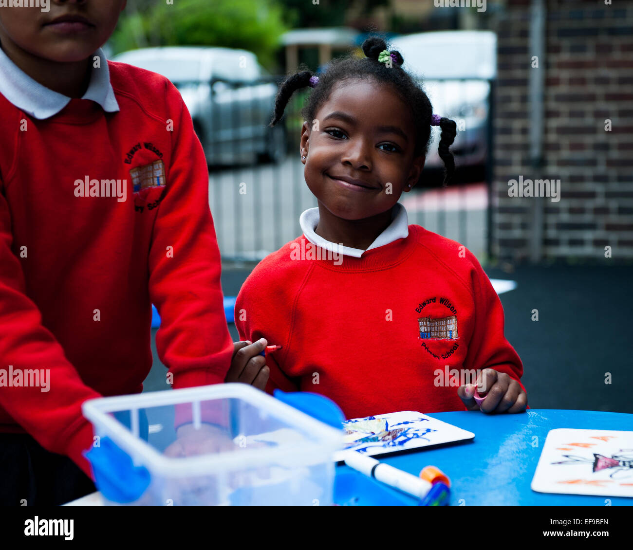Sorridenti dei bambini che giocano nel parco giochi della scuola primaria in London W2 Foto Stock