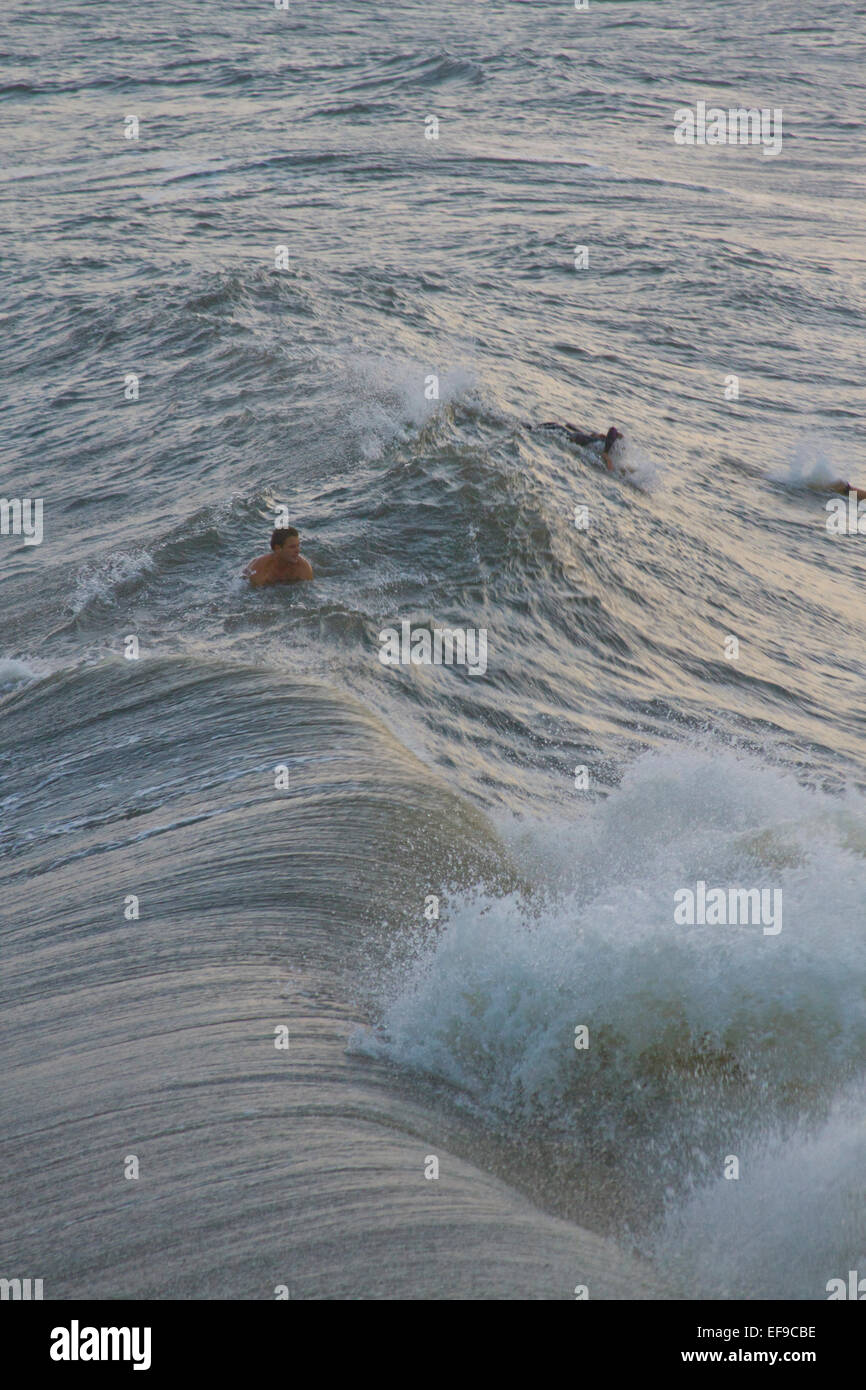 Visto dal di sopra, un surfista maschio nuota tra due grandi onde dell'oceano dalla sabbia di uragano Foto Stock