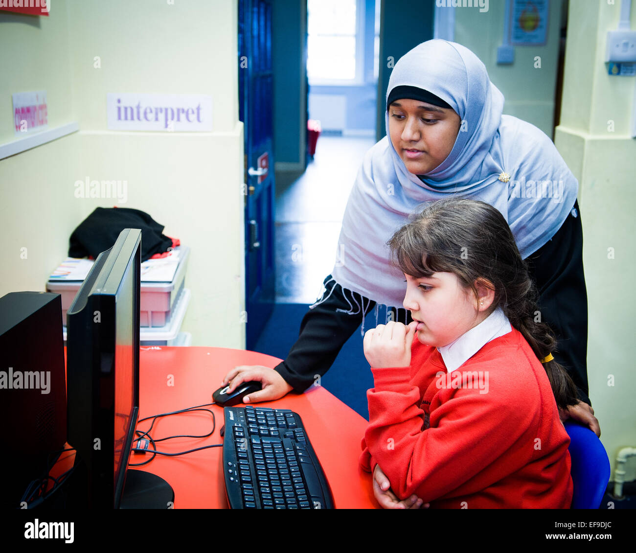 Insegnante musulmano in velo aiutando la pupilla con il computer di lavoro Foto Stock