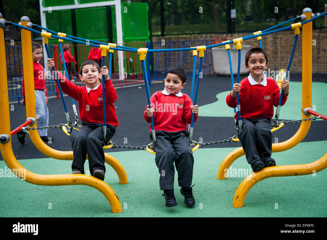 Sorridenti dei bambini che giocano nel parco giochi della scuola primaria in London W2 Foto Stock