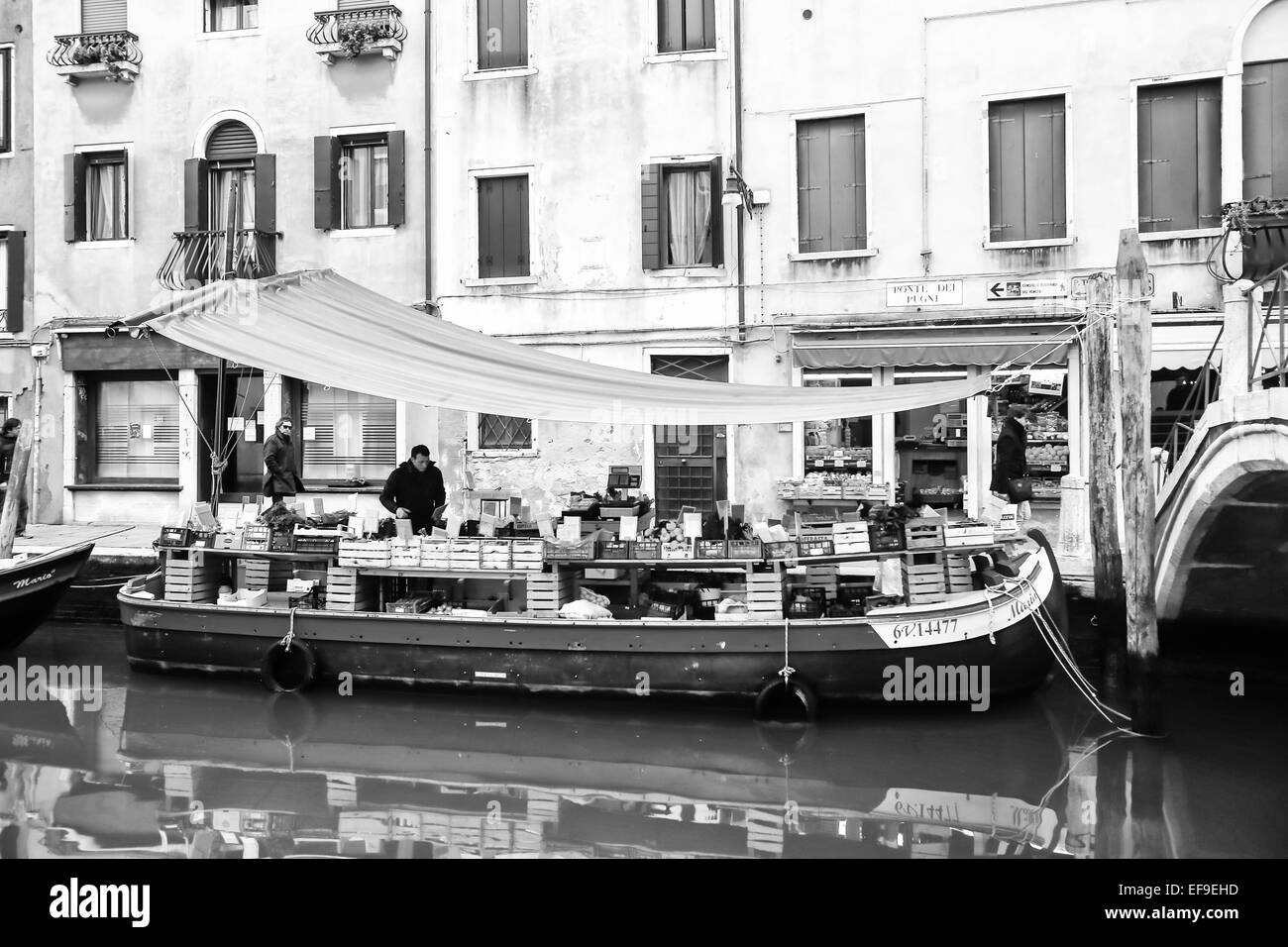 Mercato di frutta e verdura posto su una barca in un canale d'acqua con persone a piedi in strada a Venezia, Italia. Foto Stock