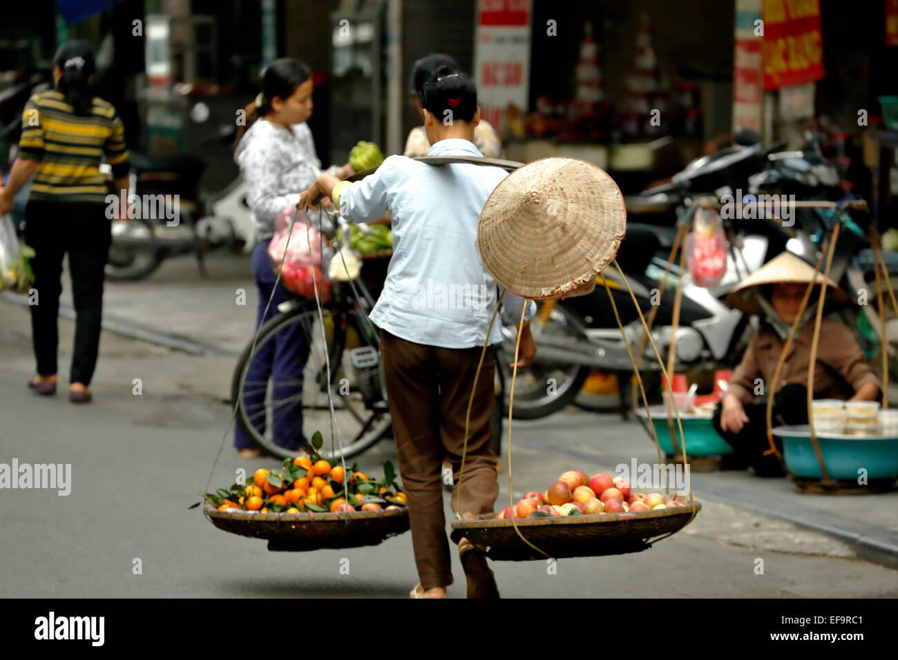 Uomo che porta frutto sul doppio cestello, Quartiere Vecchio (aka il 36 strade), Hanoi, Vietnam Foto Stock