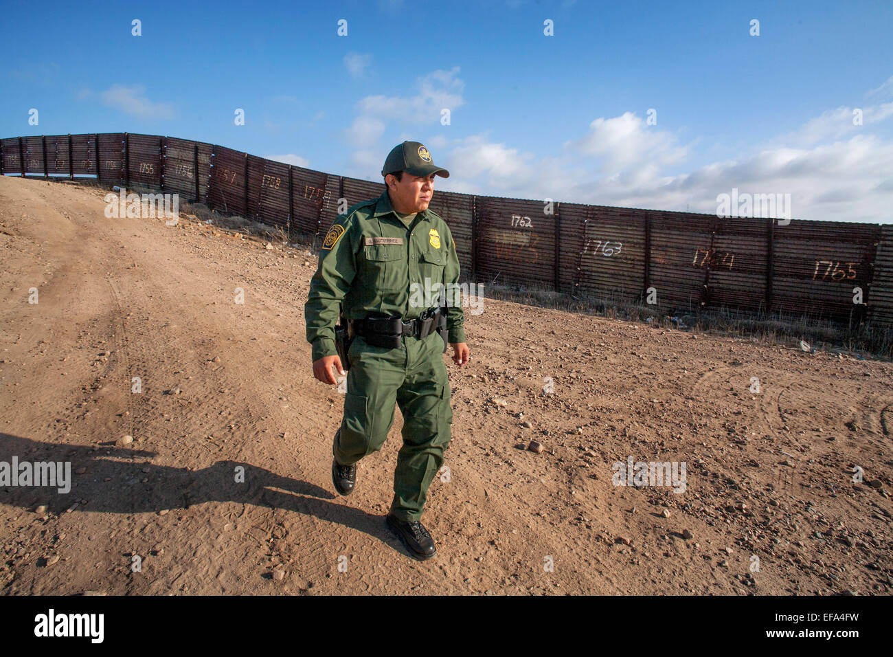 Polizia della "Bunker Hill' area dell'U.S./Messico Confine vicino Tijuana, una frontiera ispanica ufficiale di pattuglia passeggiate lungo la recinzione di confine. La Pattuglia di Confine è parte dell'U.S. Department of Homeland Security. Nota numerata su pannelli di recinzione per determinare la posizione. Foto Stock