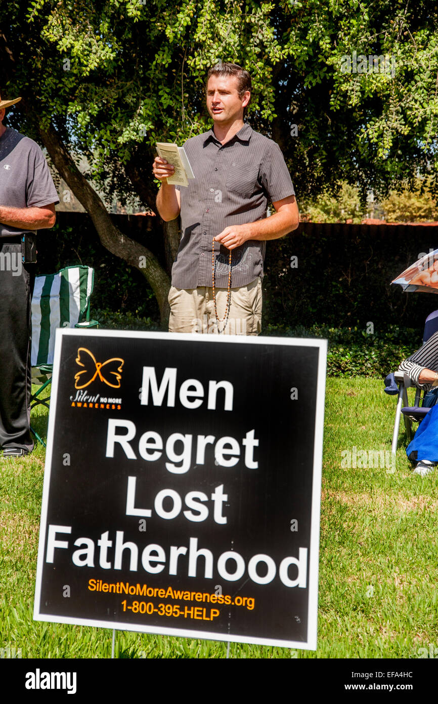 Tenendo un rosario, un uomo cattolico si oppongono all'aborto assiste un prolife veglia su un angolo di strada in Mission Viejo, CA. Nota sign in primo piano. Foto Stock