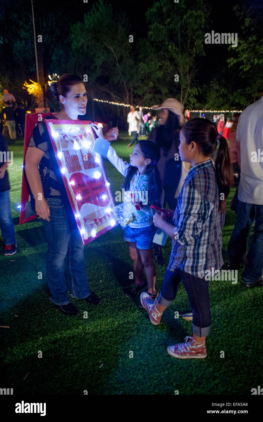 Un volontario femmina porta un sandwich illuminato consiglio segno pubblicità asta silente durante una serata Harvest fiera presso una scuola privata a Lake Forest, CA. Foto Stock