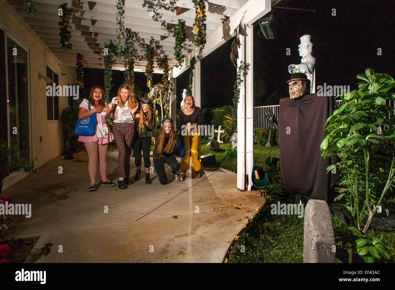 Urlando appropriatamente in un fantasma (destra) cinque giovani donne di entrare nello spirito di una notte di Halloween "Haunted Mansion' in Lake Forest, CA. Foto Stock