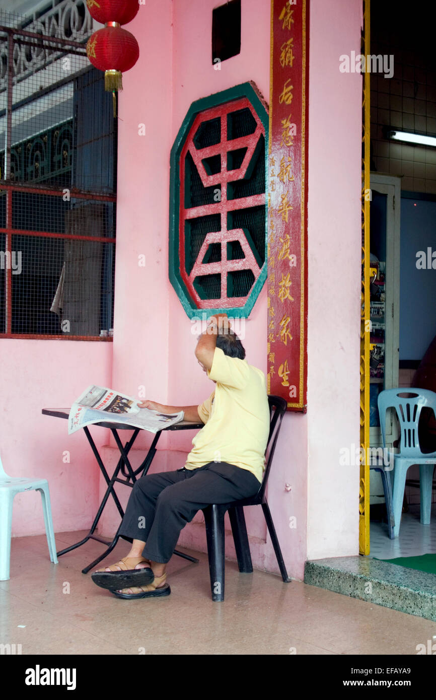 Un uomo asiatico è la lettura di una lingua cinese quotidiano nella centrale di Phnom Penh Cambogia. Foto Stock