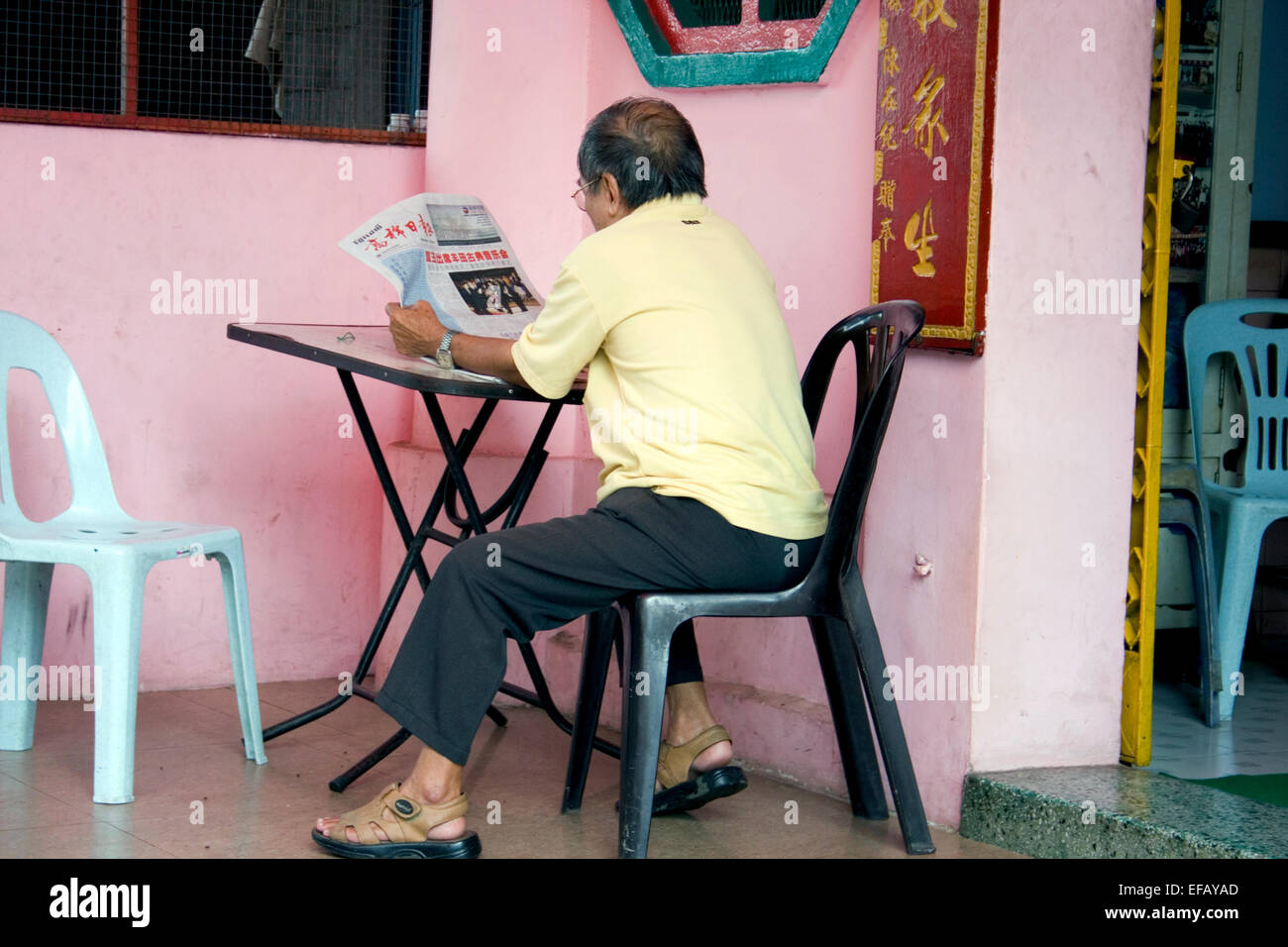 Un uomo asiatico è la lettura di una lingua cinese quotidiano nella centrale di Phnom Penh Cambogia. Foto Stock