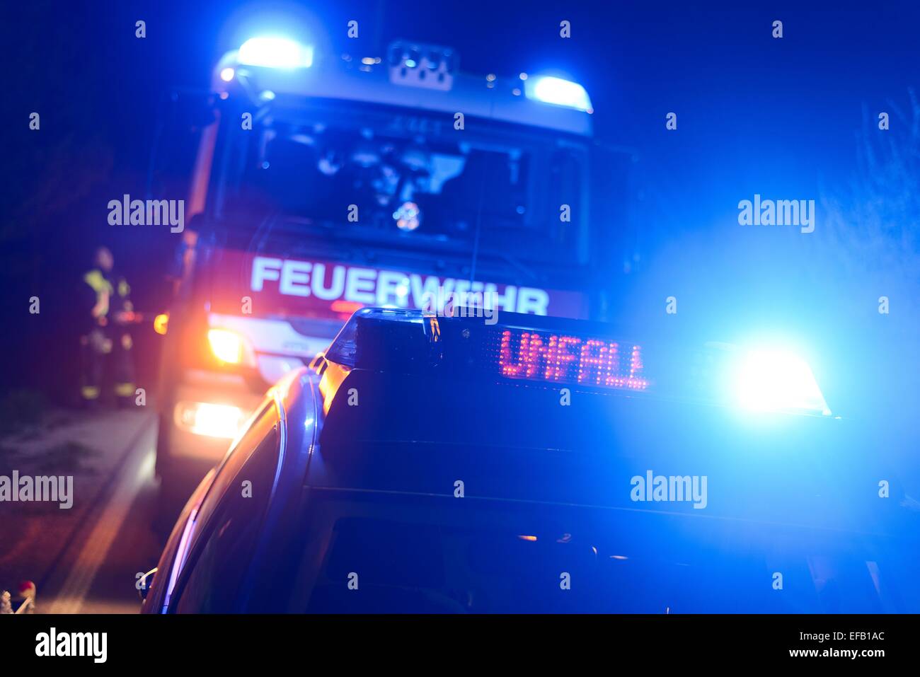 Motore Fire e auto della polizia lampeggiante con luci blu e il display LED 'Unfall', tedesco per "incidente", a un sito del crash Foto Stock