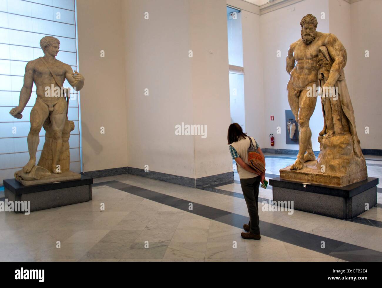 Un visitatore lookig alla statua di Ercole Farnese, esposta al Museo Archeologico Nazionale di Napoli Foto Stock