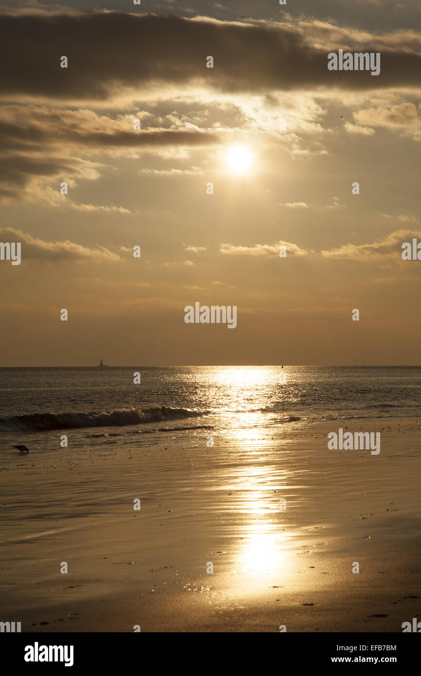 Nel tardo pomeriggio sun sfiora in tutta l'acqua sulla spiaggia a Coney Island, Brooklyn, New York. Foto Stock