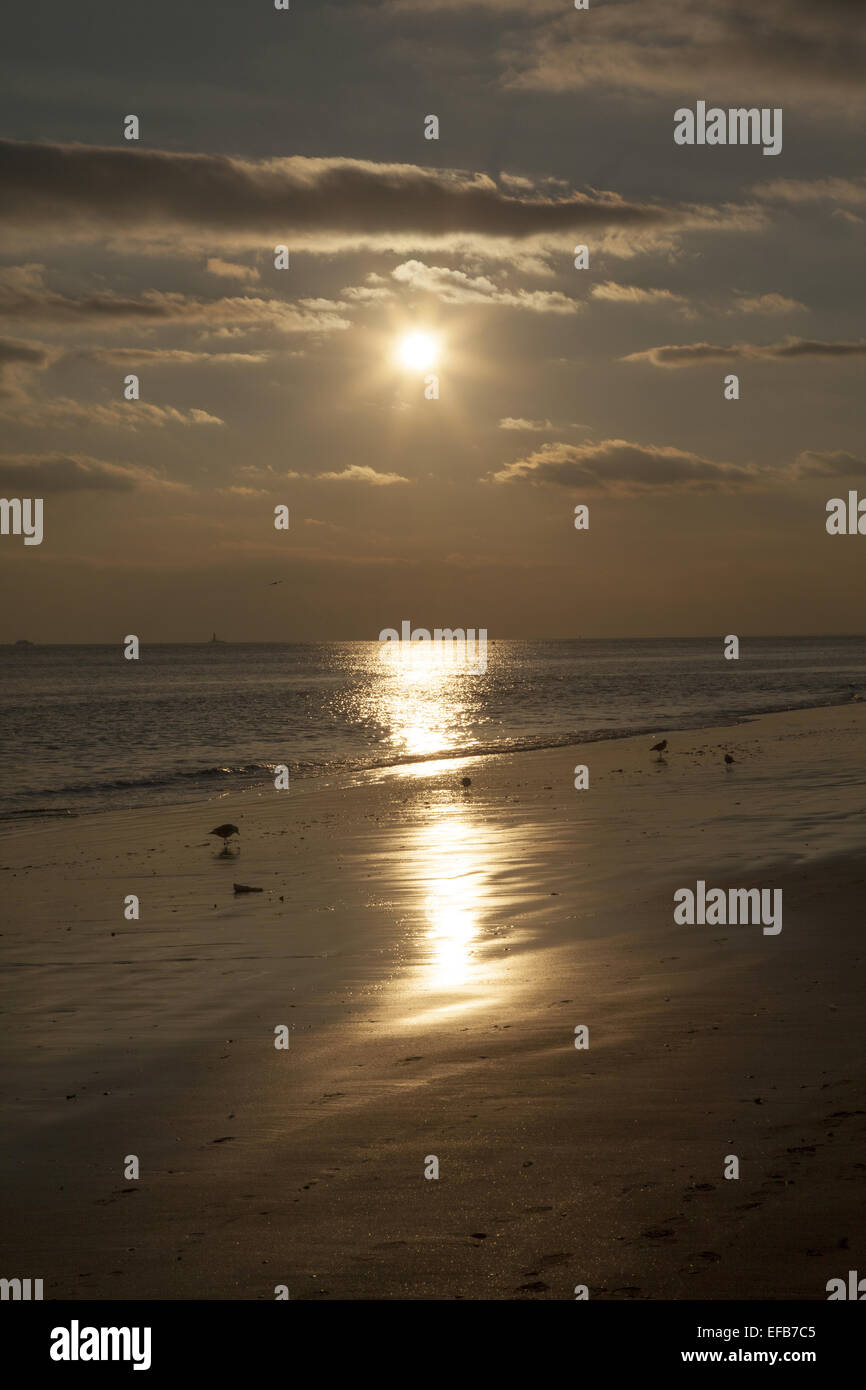 Nel tardo pomeriggio sun sfiora in tutta l'acqua sulla spiaggia a Coney Island, Brooklyn, New York. Foto Stock