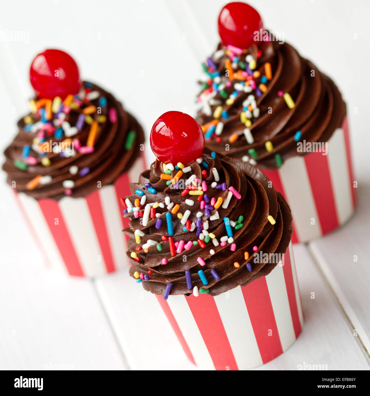 Tortine decorate con glassa di cioccolato e ciliegie al maraschino Foto Stock