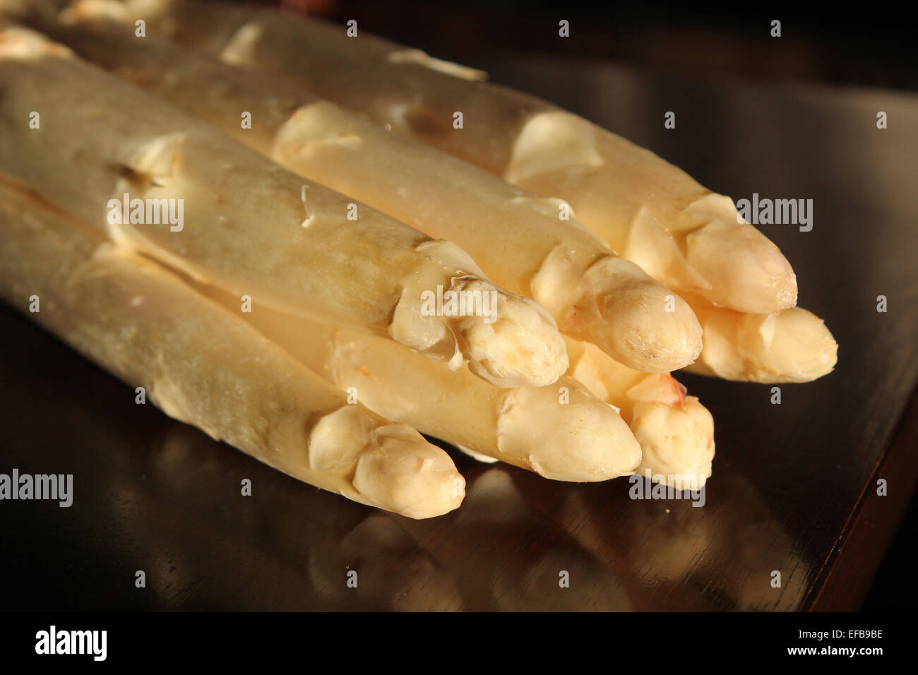 L'immagine orizzontale di una pila di sette asparagi bianchi seduta su di un legno di ciliegio tavolo. Golden morbida luce naturale Foto Stock