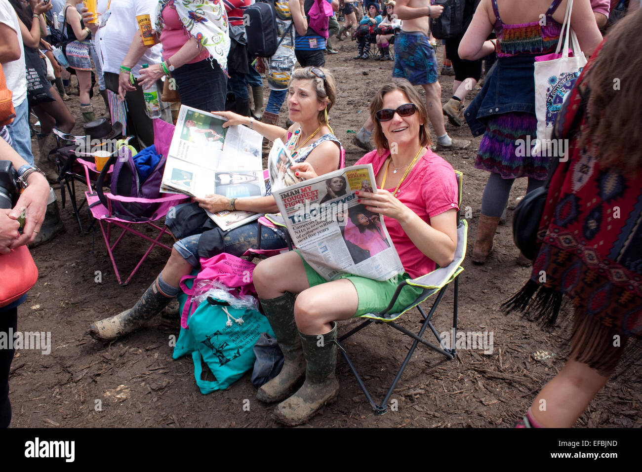Il 29 giugno 2014. Gli scommettitori di leggere i giornali vicino alla fase della piramide a Glastonbury. Foto Stock