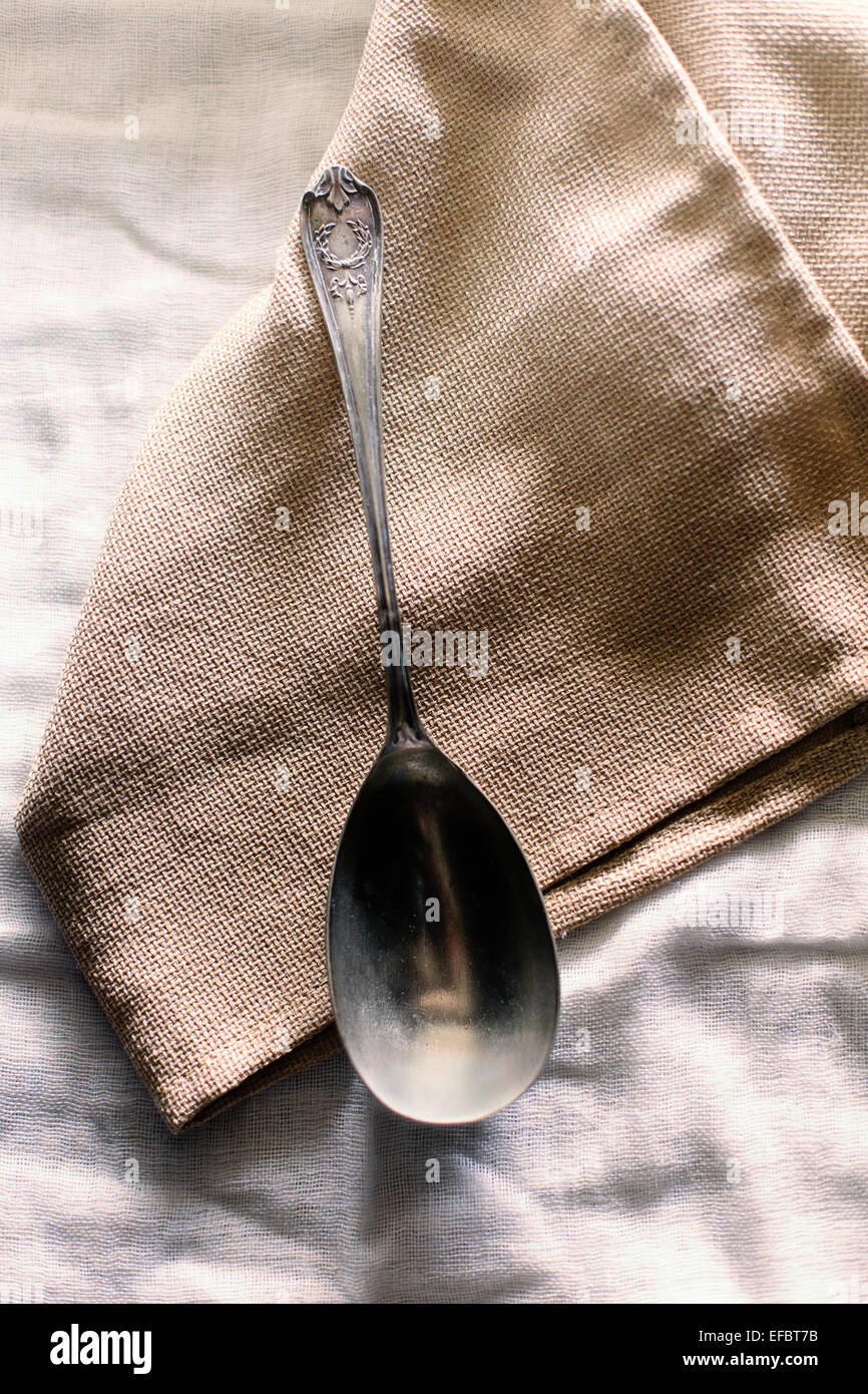 Cucchiaio d'argento su Hessian come tovagliolo sulla biancheria casual tovaglia Foto Stock
