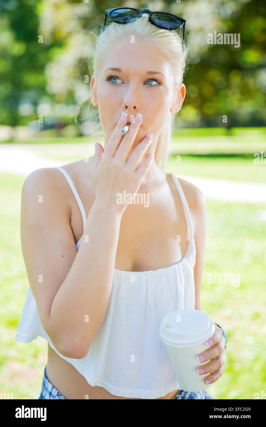 Giovane donna con problemi di fumo in posizione di parcheggio Foto Stock