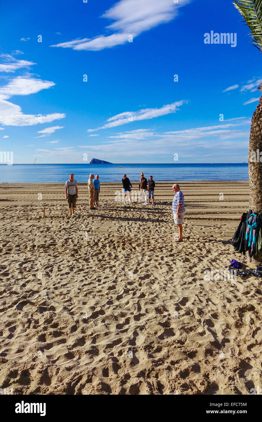 I pensionati e gli anziani a giocare palla di gioco sulla spiaggia, Peacock Island in background, Benidorm Costa Blanca, Spagna Foto Stock