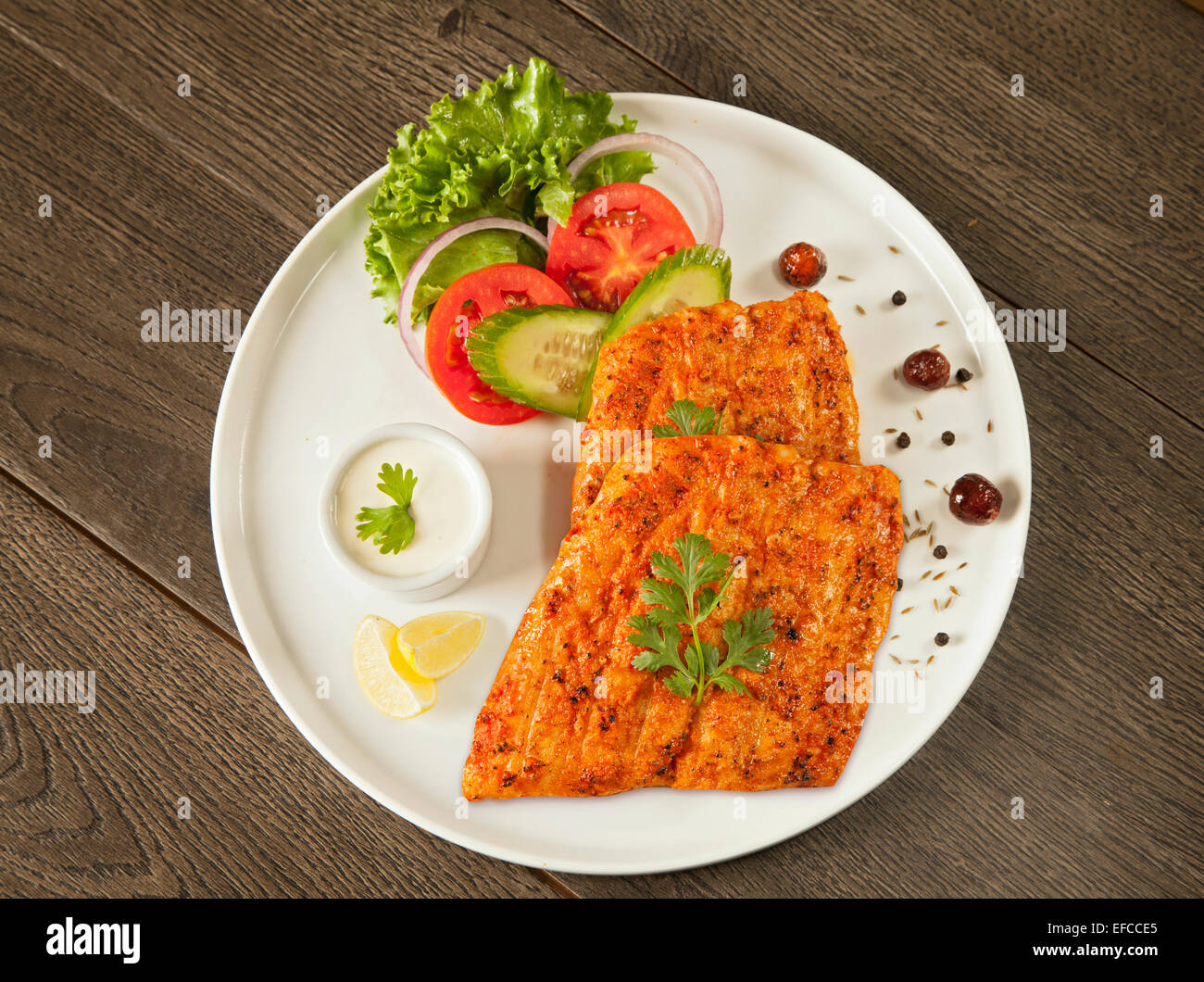 Grigliate di pesce tikka servita su una piastra con insalata e tarter salsa antenna top shot Foto Stock
