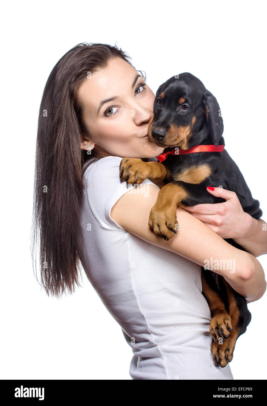 Bruna ragazza baciare il suo cucciolo doberman isolati su sfondo bianco Foto Stock