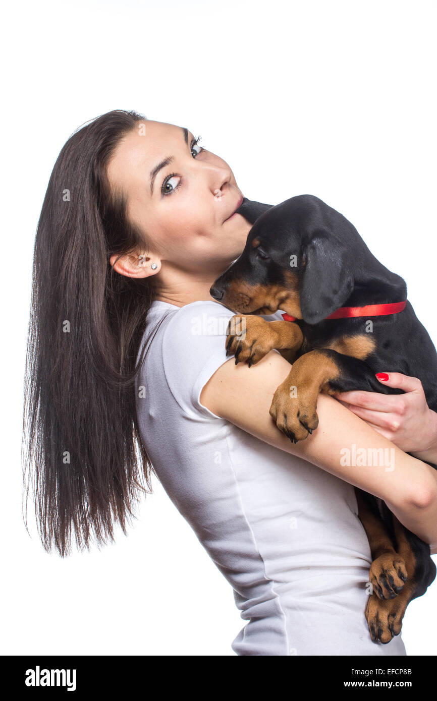 Bruna ragazza baciare il suo cucciolo doberman isolati su sfondo bianco Foto Stock