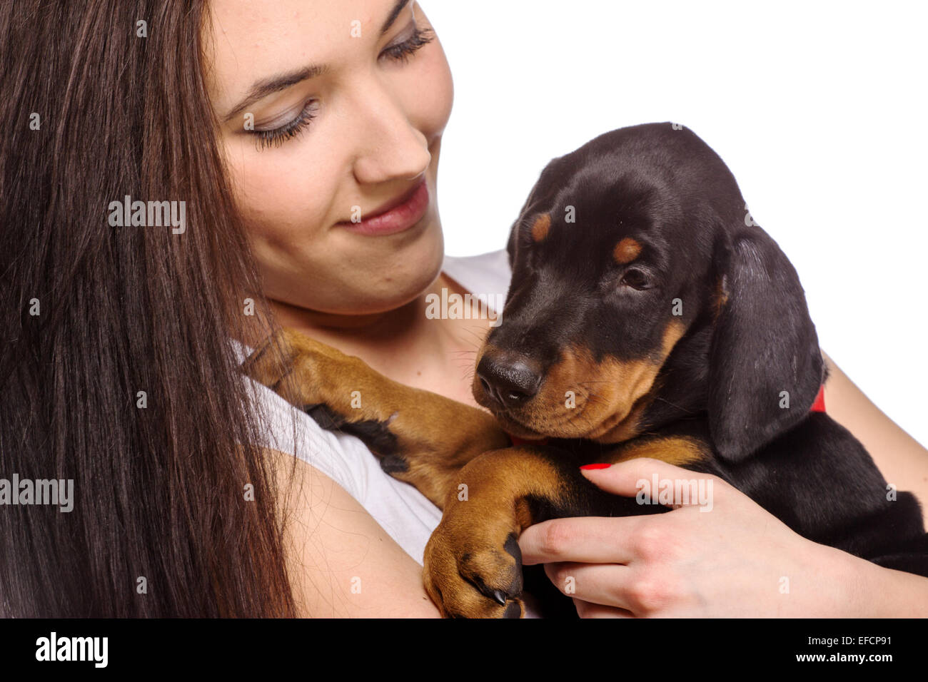 Bruna ragazza baciare il suo cucciolo doberman isolati su sfondo bianco Foto Stock