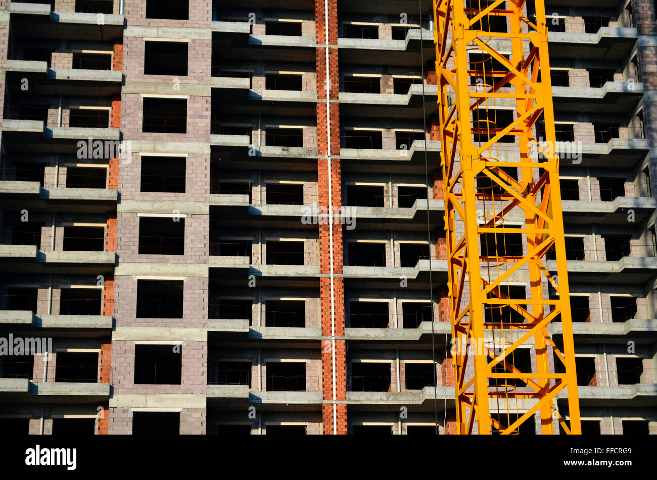Blocchi ripetitivi di piani dell'edificio in costruzione con gru giallo Foto Stock