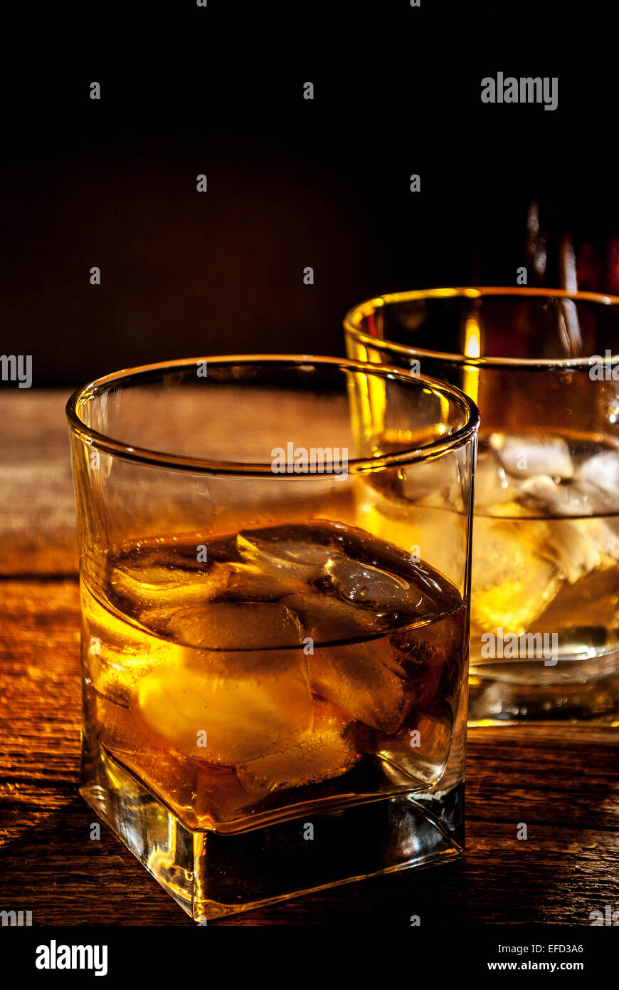Whiskey bourbon o rum marrone con ghiaccio sulla tavola di legno Foto Stock