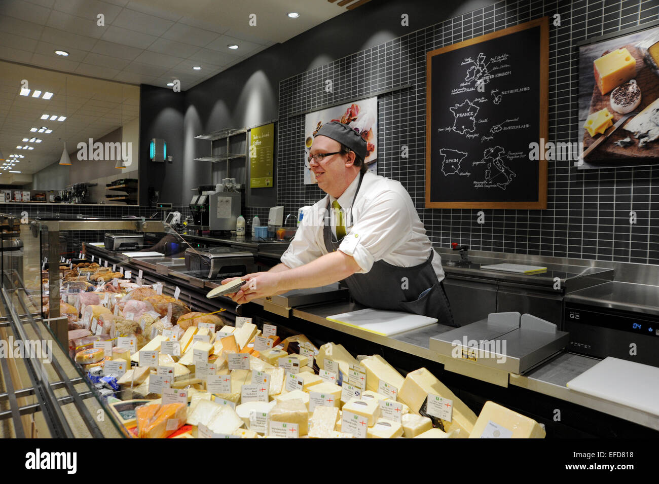 Giovane uomo che lavora sul contatore di formaggio in un supermercato Waitrose REGNO UNITO Foto Stock