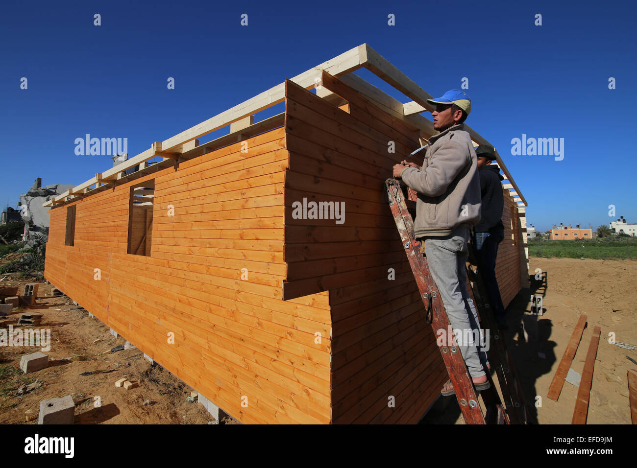 La striscia di Gaza. Il 1° febbraio 2015. I lavoratori palestinesi i lavori per la costruzione di una nuova casa di legno nel sud della striscia di Gaza city di Khan Yonis, il 1 febbraio, 2015. In un tentativo di ricostruire la guerra-case strappati nella Striscia di Gaza sotto le circostanze della mancanza di materiali di costruzione, palestinesi residenti ha iniziato a costruire case di legno. Secondo gli appaltatori locali, la striscia di Gaza ha bisogno di circa 2 milioni di tonnellate di cementi e 5 milioni di tonnellate di greggio di altri materiali da costruzione per ricostruire ciò che era stato distrutto da Israele durante l'ultimo conflitto. © Khaled Omar/Xinhua/Alamy Live News Foto Stock