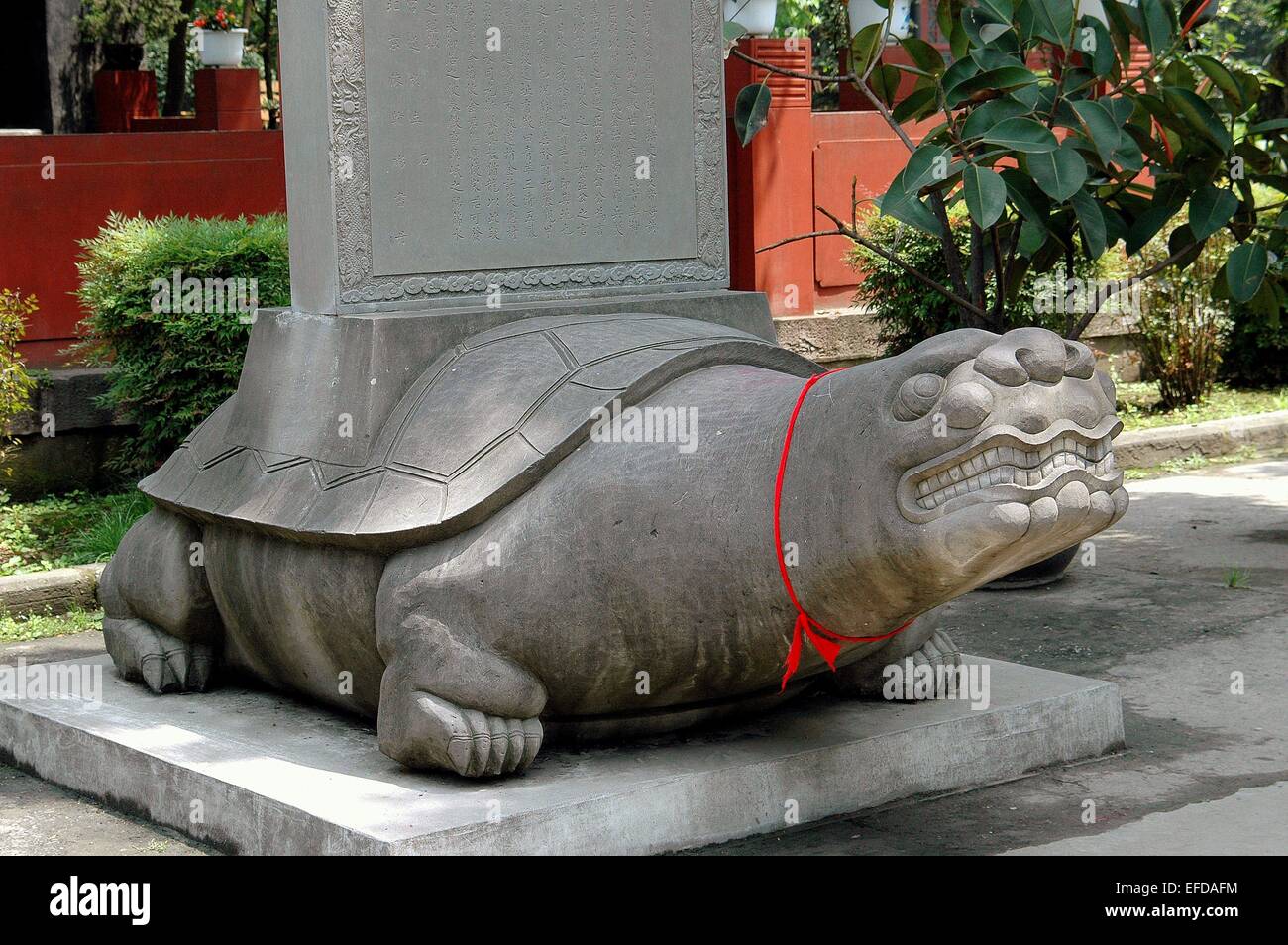 Chengdu, Cina: una grande pietra scolpita tartaruga con un nastro ROSSO intorno al suo collo alla base di una colonna Foto Stock