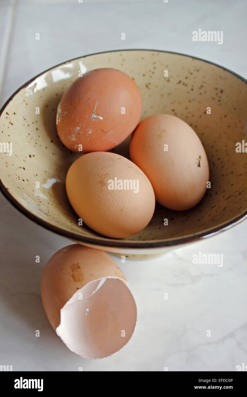 Tre free-range le uova in una ciotola più un vuoto guscio d'uovo Foto Stock
