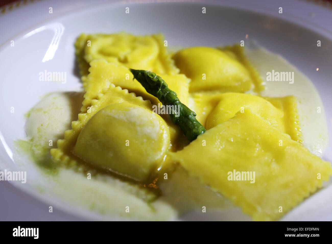 Ravioli con asparagi verdi servita in Milano, Italia. La parabola ha una salsa di formaggio cremosa. Foto Stock