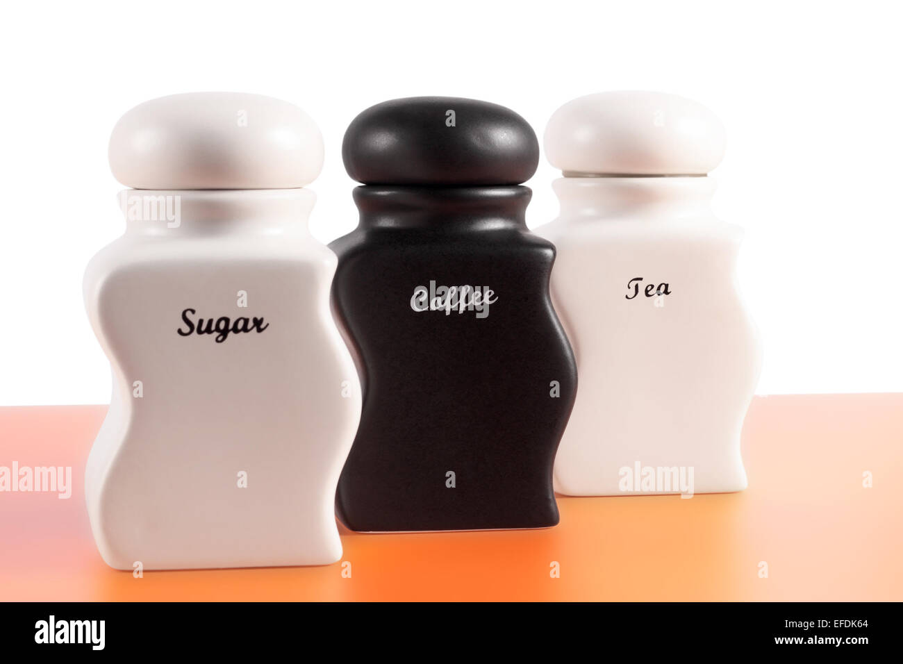 Capacità di zucchero, caffè, tè su una superficie di colore arancione e uno sfondo bianco. Foto Stock