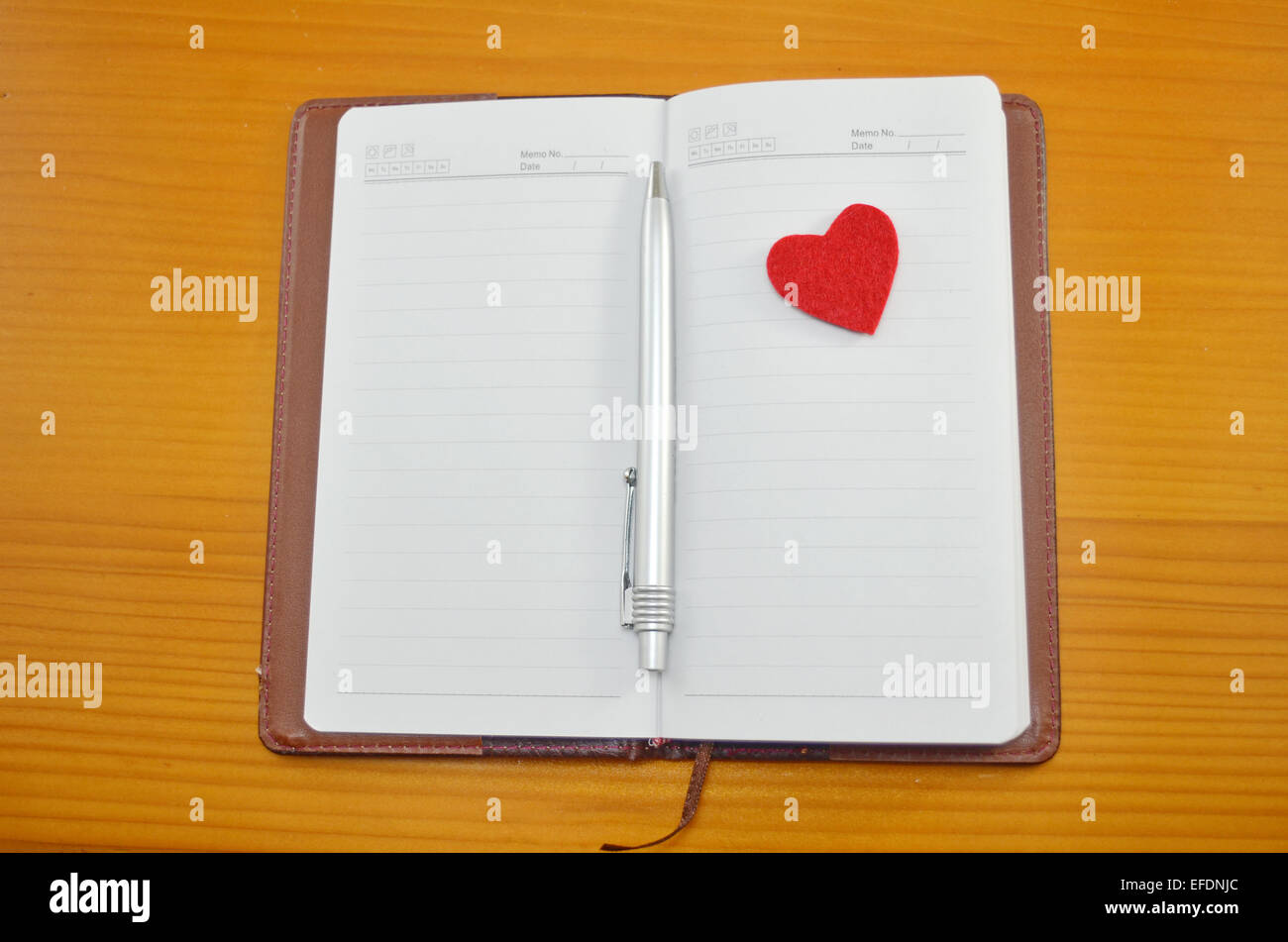 Notebook, matita e un piccolo cuore rosso su un tavolo Foto Stock