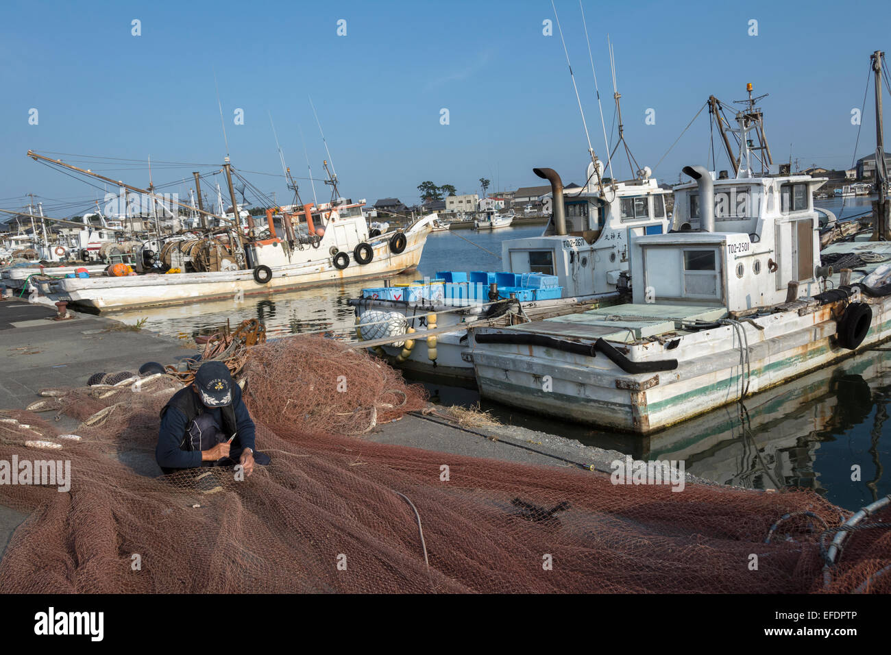 Uomo che ripara le reti da pesca alla vecchia maniera, Naruto Harbour, l'isola di Shikoku, Giappone Foto Stock