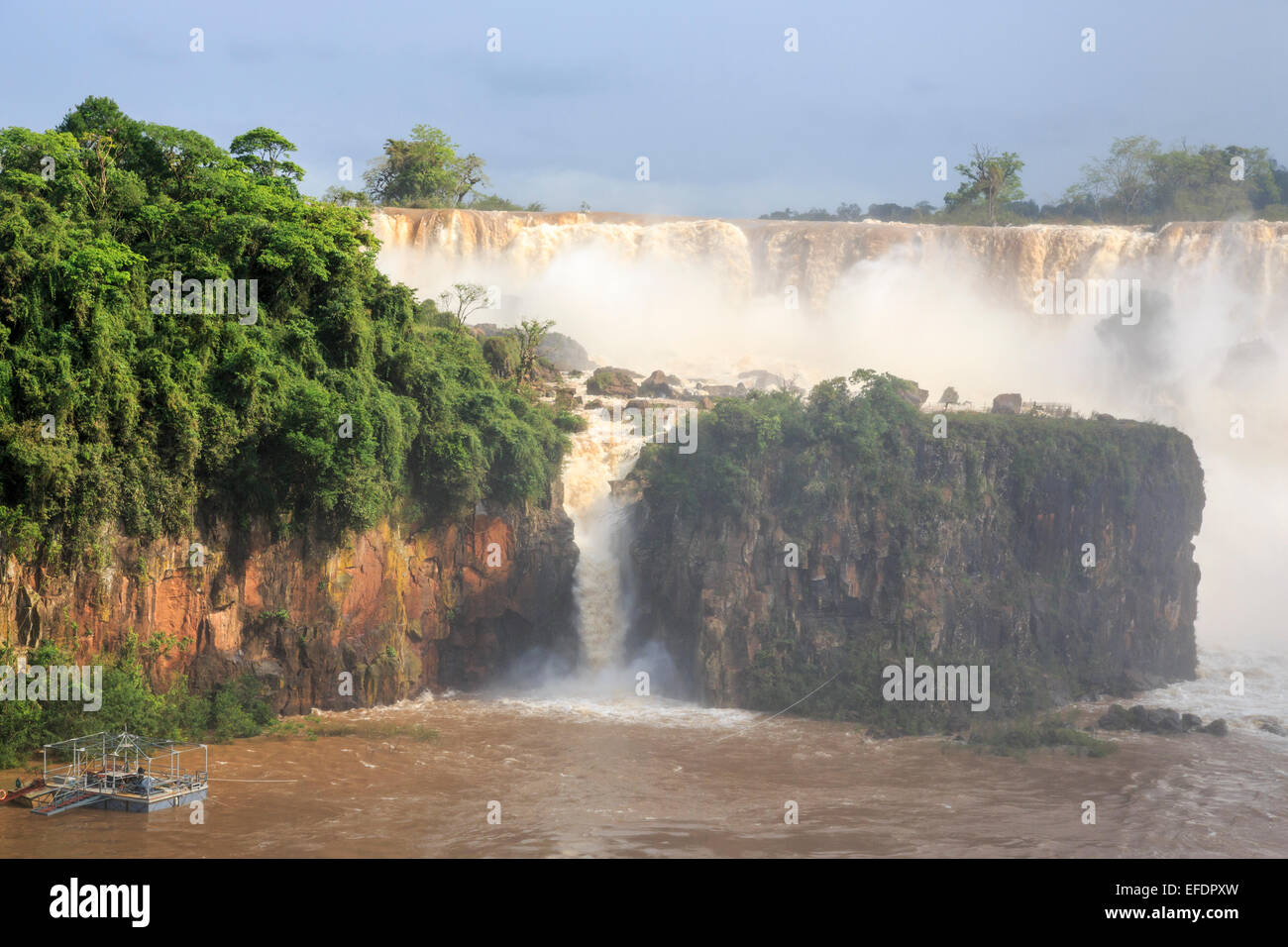 Meraviglie naturali: vista della magnifica enorme Iguazu Falls in piena ondata, visto dal lato Argentino in una giornata di sole con cielo blu Foto Stock