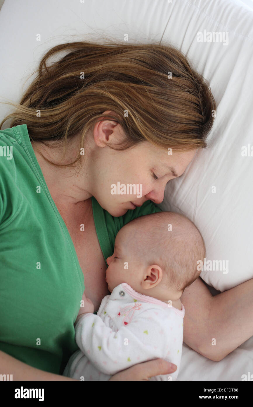 Due mesi di bambina è coccolato da sua madre mentre dorme nel letto. Foto Tim Clayton Foto Stock