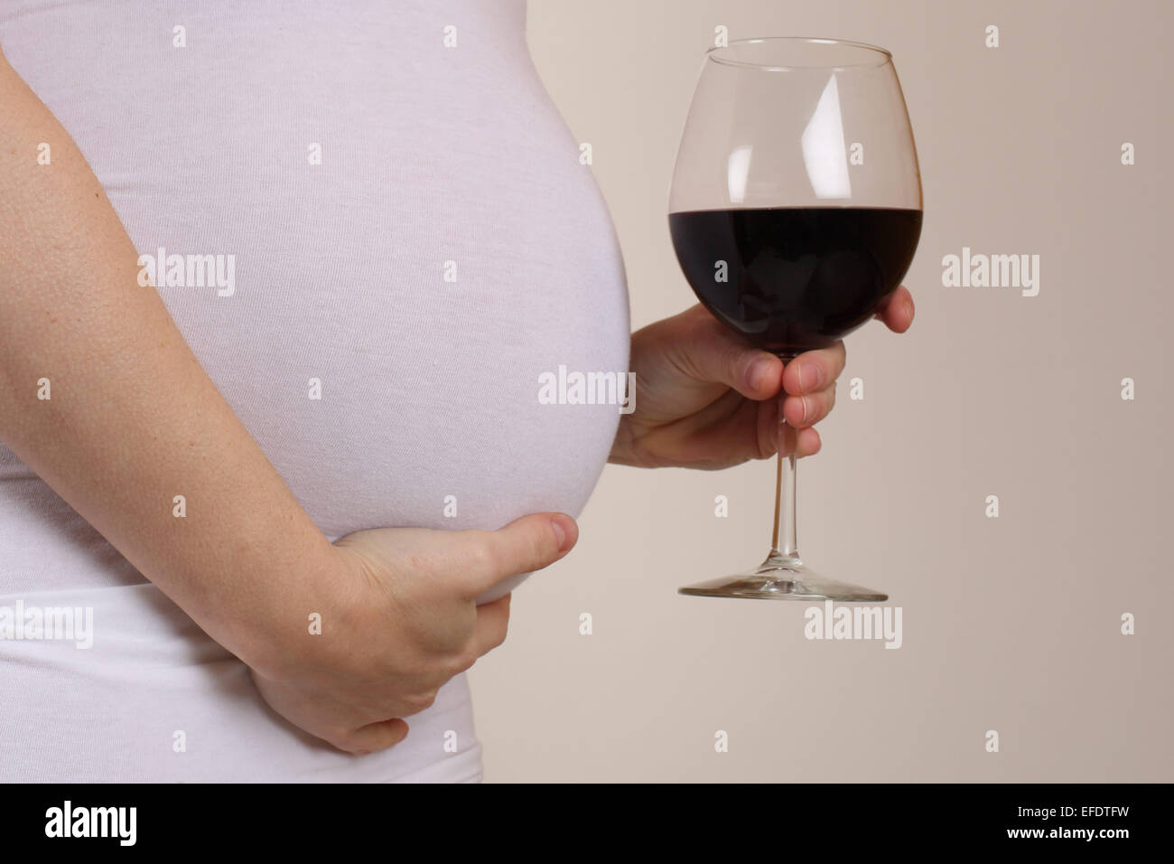 A donne in stato di gravidanza pone con un bicchiere di vino rosso. Foto Tim Clayton Foto Stock