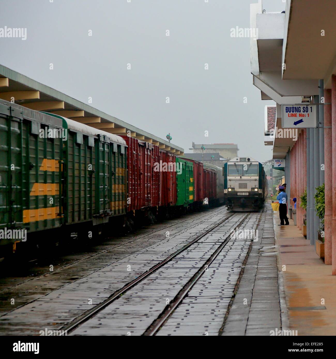 Un treno merci attende su un binario alla stazione di Hue mentre il treno per da Nang si avvicina sull'altro binario Foto Stock