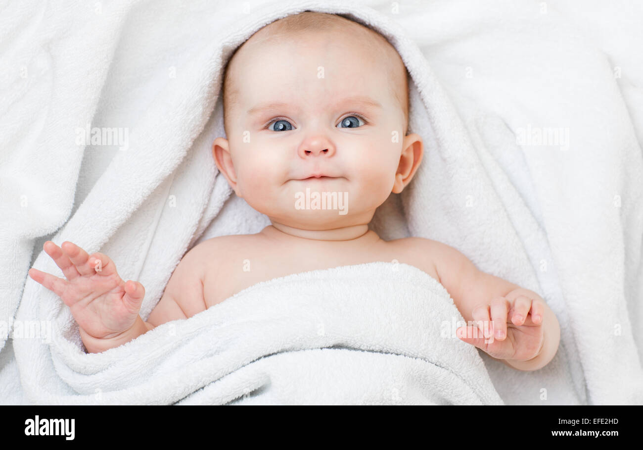 Carino sorridente divertenti baby sdraiato sulla schiena in asciugamano di balneazione Foto Stock
