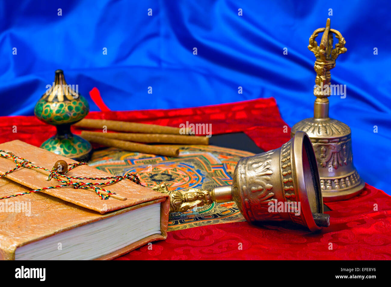 Due rituali tibetani campana e un libro su uno sfondo blu Foto Stock