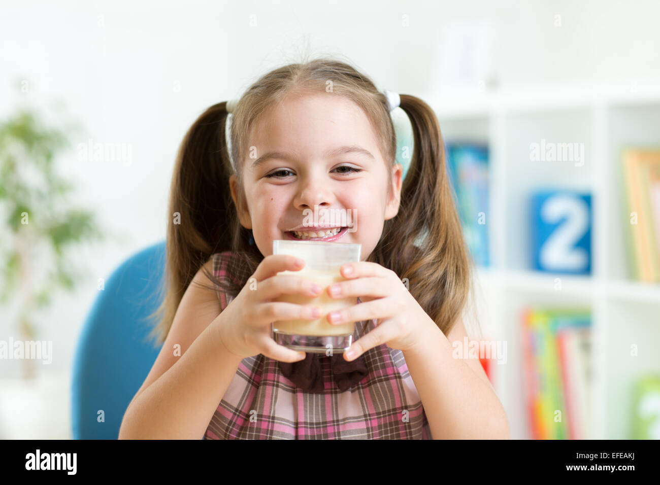 Bambina bere latte dal vetro indoor Foto Stock