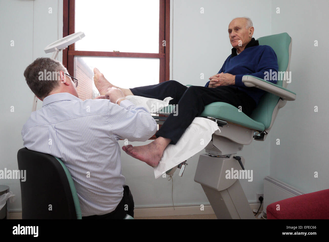 Un uomo anziano con demenza che viene trattata da un pedicure in una sedia di trattamento. Foto Stock