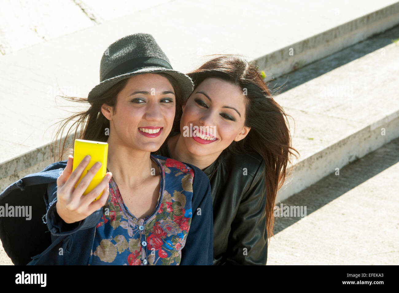 Amici divertendosi in città prendendo selfie seduti su un staricase Foto Stock