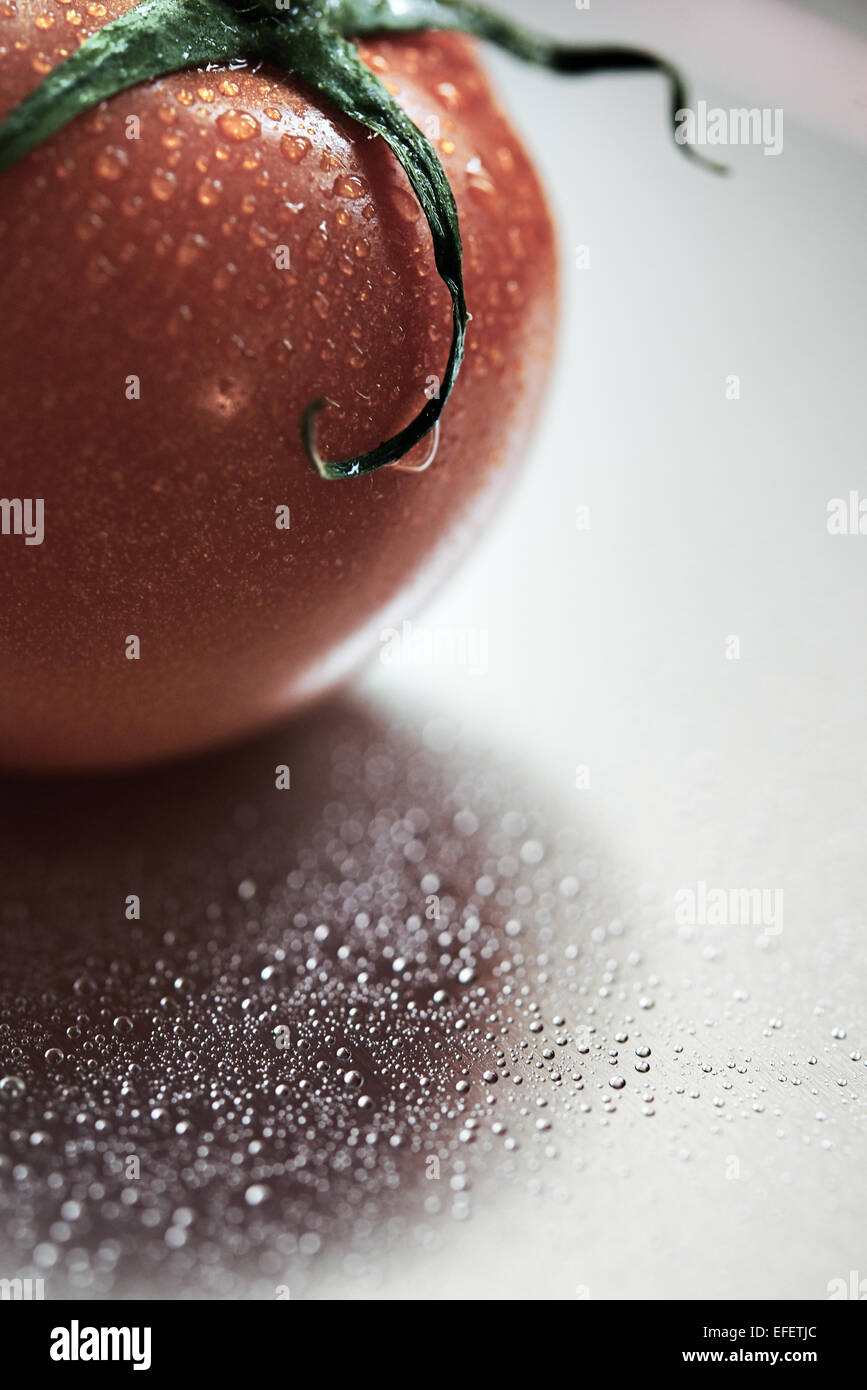 Il pomodoro con goccioline di acqua contro uno sfondo color argento Foto Stock